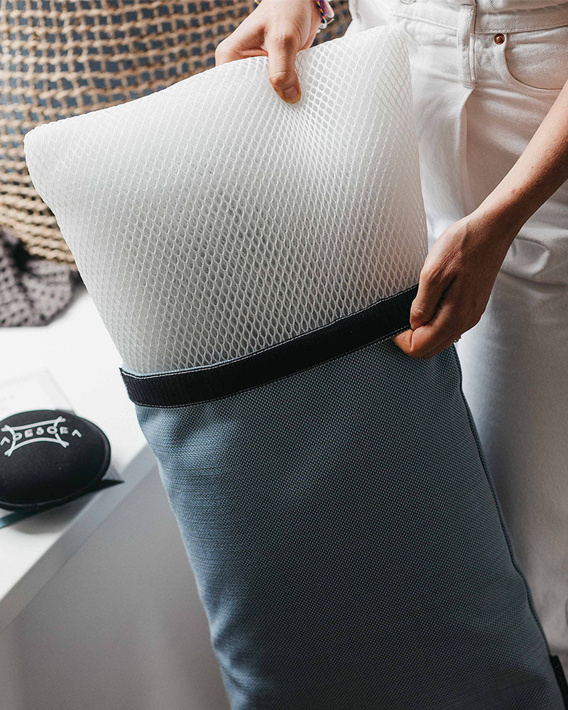 Detailaufnahme, wie eine Person das Innenkissen aus 3D-Mesh aus einem Badesofa Fusskissenbezug herauszieht.