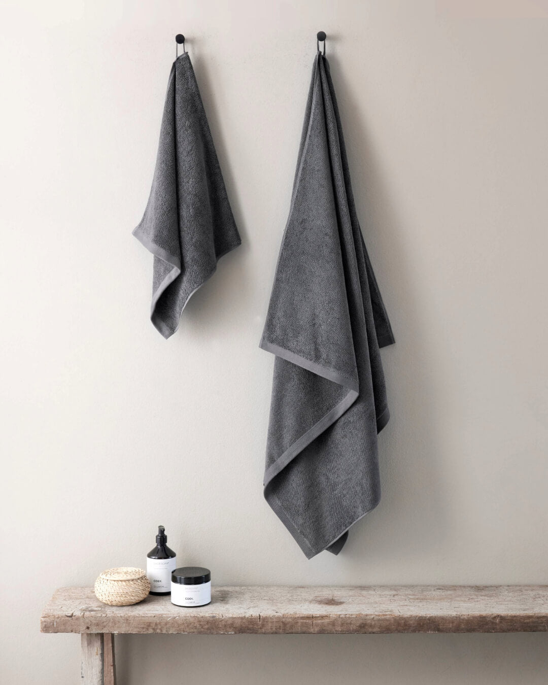 Ein Handtuch und ein Badetuch hängen an Haken an der Wand, Farbe Anthrazit