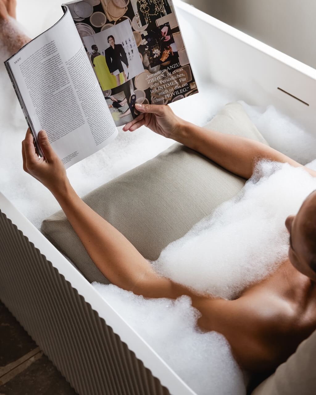 Nahaufnahme, wie Arme entspannt beim Baden auf einem Badesofa liegen.