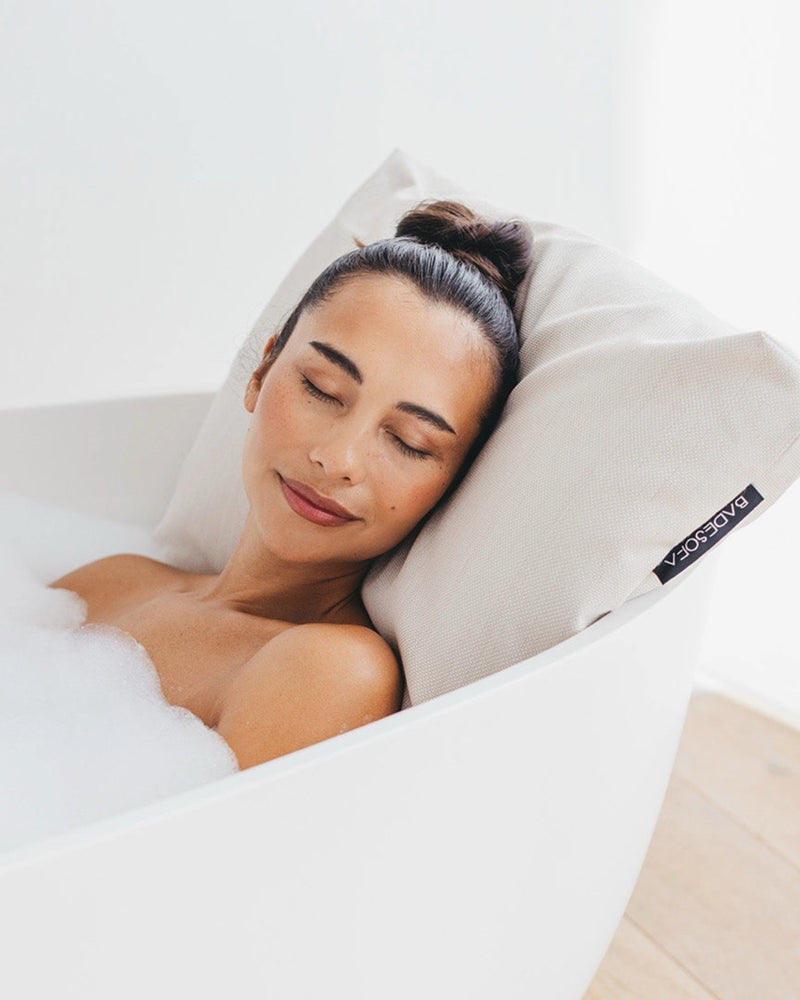Perlmutt Badesofa Rückenkissen (Size Large) in einer freistehenden Badewanne, mit einer Frau, die sich entspannt anlehnt. 